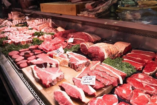Different cuts of beef displayed at a traditional butcher’s counter.